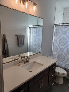a bathroom with a sink and a toilet and a mirror at The Alamo Riverwalk Pearl Modern 4 Bedroom Home in San Antonio