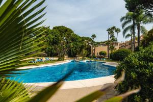 a swimming pool in a park with palm trees at Elviria beach Award-Winning Stay in Marbella