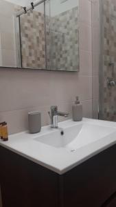 een badkamer met een witte wastafel en een spiegel bij La casa di Angy in Acquaviva delle Fonti