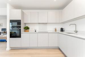 a white kitchen with white cabinets and appliances at Docklands Two Bed Apartment in London