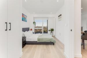 a white bedroom with a bed and a window at Docklands Two Bed Apartment in London