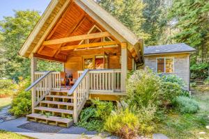 una baita di tronchi con un ampio portico e scale che vi condurranno di Guineveres Cottage a Yachats