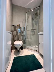 a bathroom with a shower and a toilet and a green rug at George Studio przy Stadionie Narodowym in Warsaw