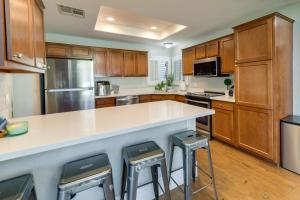 a kitchen with wooden cabinets and a large island with bar stools at Spacious Gilbert Vacation Rental Near Water Ranch! in Gilbert