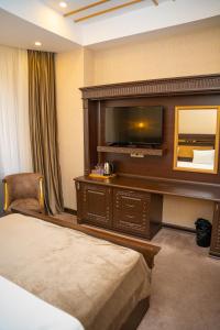 ein Hotelzimmer mit einem Bett und einem Flachbild-TV in der Unterkunft The Krone in Baku