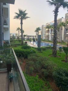 a balcony of a building with palm trees and a pool at Appartement Casablanca in Dar Bouazza +7 photos