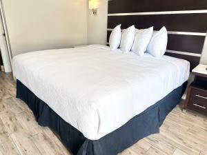 Cama grande en habitación de hotel con sábanas y almohadas blancas en Americas Best Value Inn Arlington, en Arlington