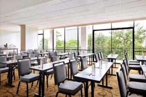 uma sala de jantar com mesas, cadeiras e janelas em San Antonio Marriott Riverwalk em San Antonio