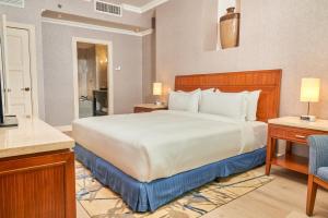 een slaapkamer met een groot wit bed en een stoel bij Waymore Hotel Spa & Casino in Panama-Stad
