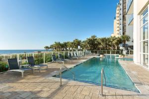 默特尔比奇Hilton Grand Vacations Club Ocean 22 Myrtle Beach的一个带椅子的游泳池,背景是大海
