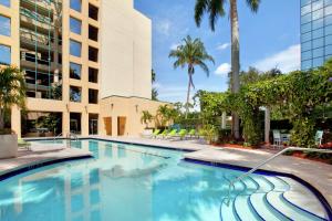 a swimming pool at a hotel with palm trees at Hilton Boca Raton Suites in Boca Raton