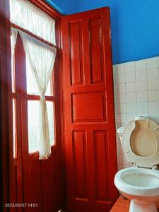 La salle de bains est pourvue d'une porte rouge et de toilettes. dans l'établissement Hotel Casa del Artillero, à Pátzcuaro
