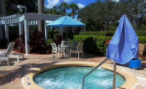 a swimming pool with a blue umbrella and a table and chairs at Hilton Boca Raton Suites - Newly Renovated in Boca Raton +38 photos