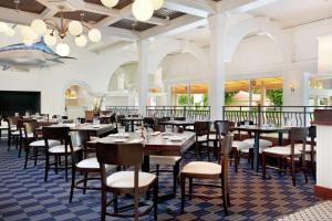 Hilton Boca Raton Suites في بوكا راتون: غرفة طعام مليئة بالطاولات والكراسي