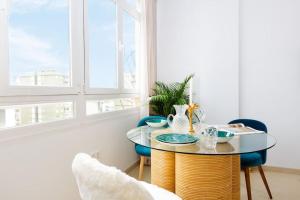 comedor con mesa de cristal y sillas azules en Palm Suite, en Torremolinos