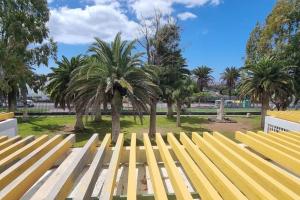 a yellow bench in a park with palm trees at Apartamento D&L in Costa Del Silencio