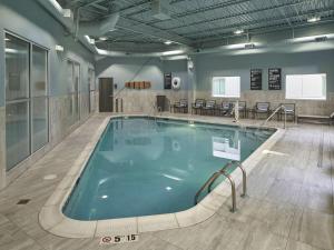 a large swimming pool in a room with tables and chairs at Hilton Cincinnati Airport in Florence