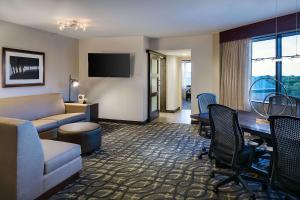 a hotel room with a couch and a table and a desk at Embassy Suites by Hilton Dallas-Love Field in Dallas