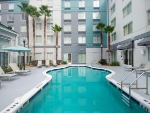 a swimming pool in the courtyard of a building with palm trees at Hilton Garden Inn Jacksonville JTB/Deerwood Park in Jacksonville