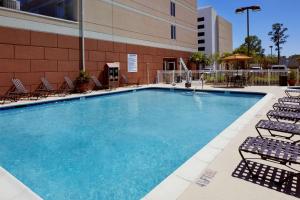 Hilton Garden Inn Savannah Midtown في سافانا: مسبح كبير مع كراسي ومبنى
