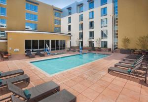a pool in a courtyard with chairs and a building at Hilton Garden Inn Burbank Los Angeles in Burbank