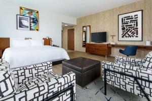 a hotel room with a bed and chairs and a television at Hampton Inn & Suites Santa Monica in Los Angeles