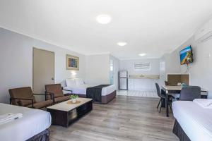 ブリスベンにあるComfort Inn North Brisbaneのベッド2台とリビングルームが備わるホテルルームです。