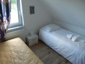 niewielka sypialnia z 2 łóżkami i oknem w obiekcie Sosnówka - domki nad morzem w mieście Kopalino