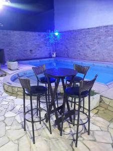 einen Tisch und Stühle vor einem Pool in der Unterkunft CASA MATTOS in São Pedro da Aldeia
