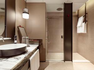 a bathroom with a sink and a shower at Swissotel The Stamford in Singapore