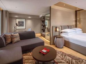 um quarto de hotel com uma cama e um sofá em Swissotel The Stamford em Singapura