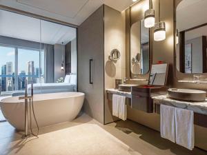 La salle de bains est pourvue d'une baignoire, de 2 lavabos et d'un lit. dans l'établissement Swissotel The Stamford, à Singapour