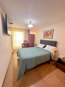 a bedroom with a large bed with a green blanket at Hotel Palmas Reales in Trujillo