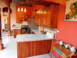 a kitchen with orange walls and wooden cabinets at Habitaciones - Casa Lester in Granada