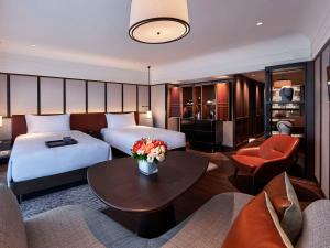 a hotel room with two beds and a table with flowers at Fairmont Singapore in Singapore