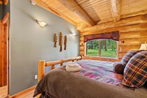a bedroom in a log cabin with a bed and a window at Big Jim Mountain Lodge in Leavenworth
