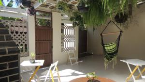 un patio con sillas, mesas y una hamaca en Casa Aconchegante en Maresias