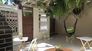 a patio with chairs and tables and a hammock at Casa Aconchegante in Maresias