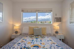 a bedroom with a bed with two lamps and a window at Kauhale Breeze in Wailea