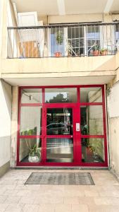 a red door on a building with plants in it at Le Color Spot - Porte de Paris in Pantin