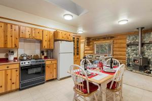 Bear Ridge Cabin في ليفنوورث: مطبخ مع طاولة وثلاجة بيضاء