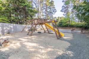 a playground with a yellow slide and a bench at Mertini in Depoe Bay