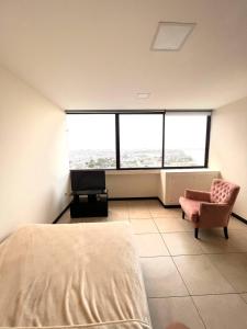 ein Schlafzimmer mit einem Bett, einem Stuhl und einem Fenster in der Unterkunft Cómodo departamento torres Bellini 4 in Guayaquil