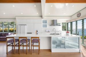 a kitchen with a large white island with bar stools at Pacific Lodge in Hyams Beach