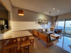 sala de estar con mesa y sofá en Sidi Rahal Blue View, Piscine & mer sans vis-à-vis en Sidi Rahal