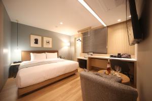 a bedroom with a bed and a desk and a chair at Hound Hotel Minam in Busan