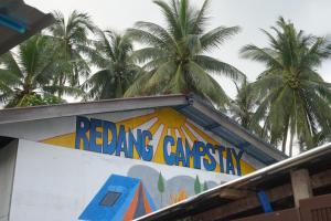 a sign on the side of a building with palm trees at Redang Campstay in Redang Island