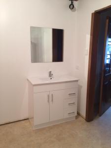 een badkamer met een witte wastafel en een spiegel bij Tranquil Point in Cygnet