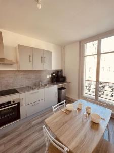 a kitchen with a wooden table with chairs and a dining room at Studio de la Belle Vue in Charleville-Mézières