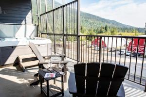 a balcony with a hot tub and a chair and a grill at Revy's Stellar Retreat in Revelstoke